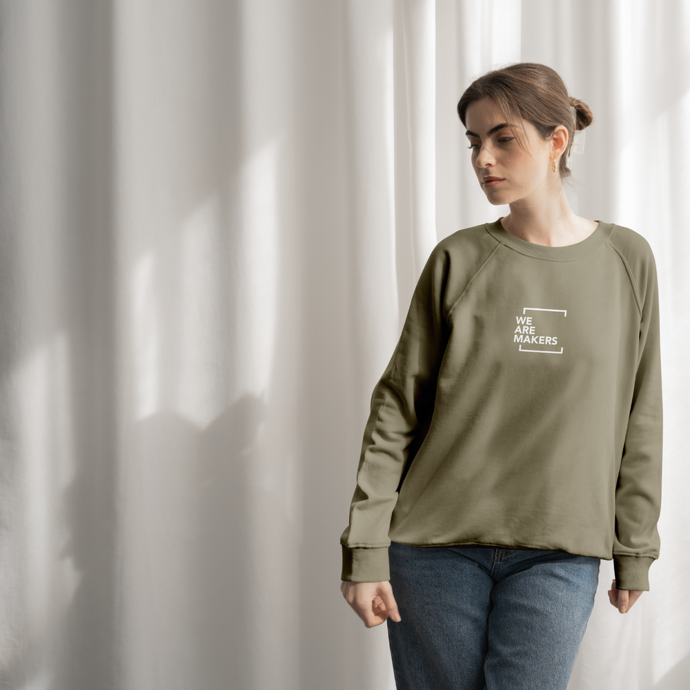 Woman wearing a green sweatshirt with text, standing against a light curtain background